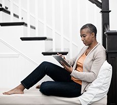 woman sitting on stairs looking at EquaMax on a tablet